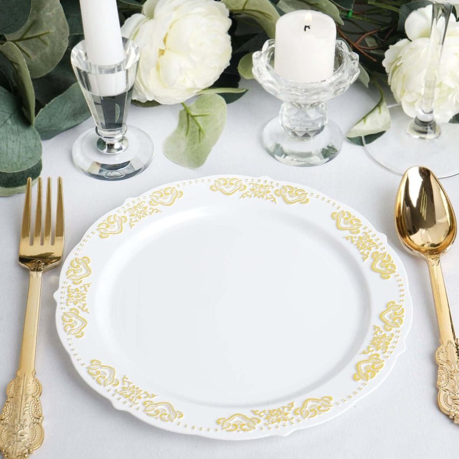 White round disposable plastic plate with decorative gold baroque rim. Elegant wedding tableware.