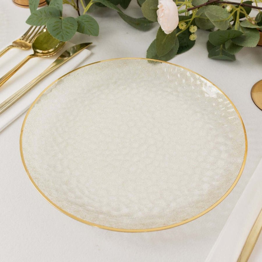 White plastic dinner plate with a gold rim. Disposable premium tableware for wedding receptions.